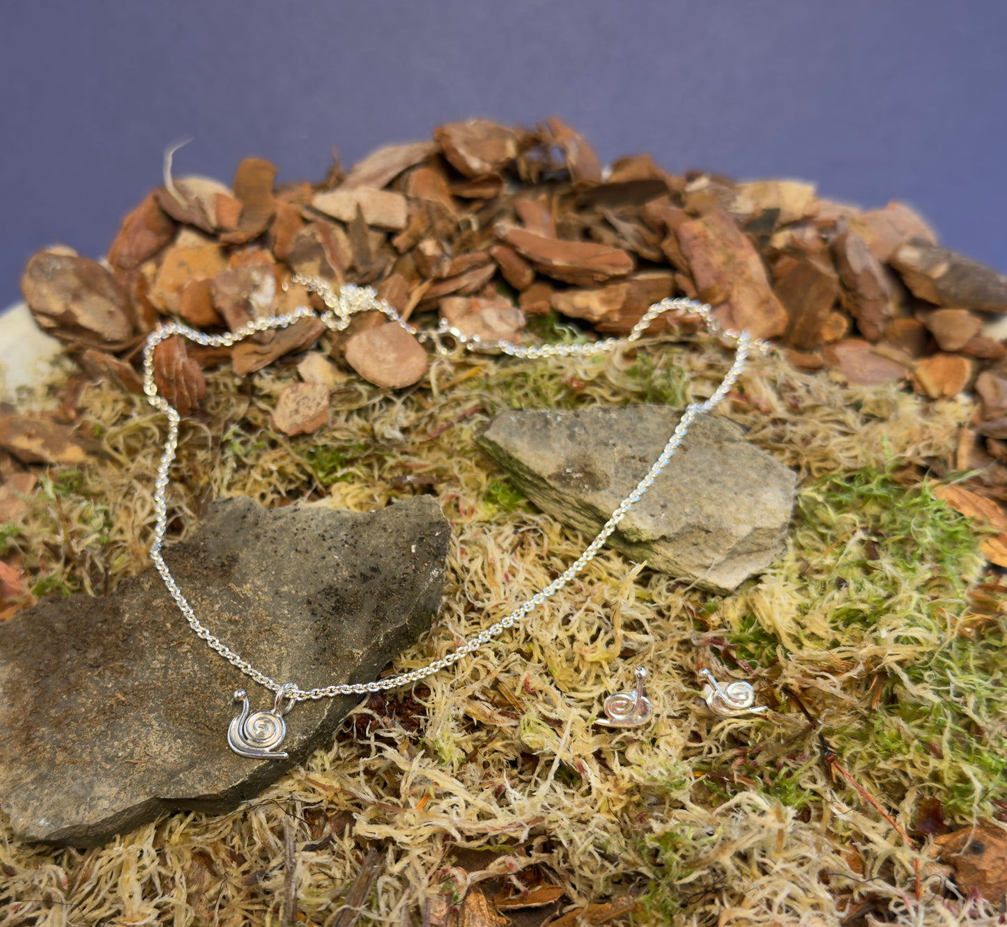 Silver necklace with a pendant on a natural stone and moss background
