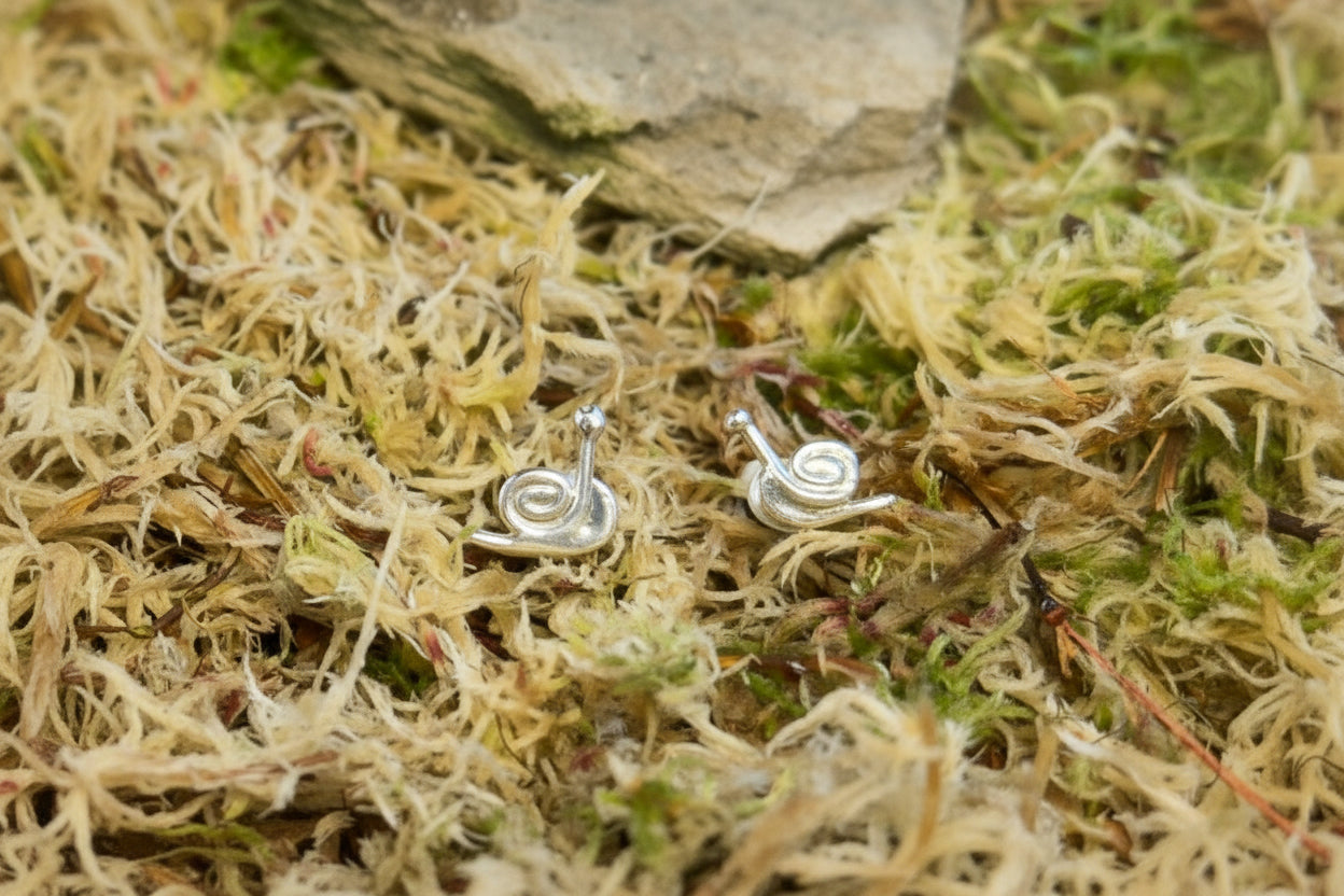 Silver snail studs on a natural stone and moss background