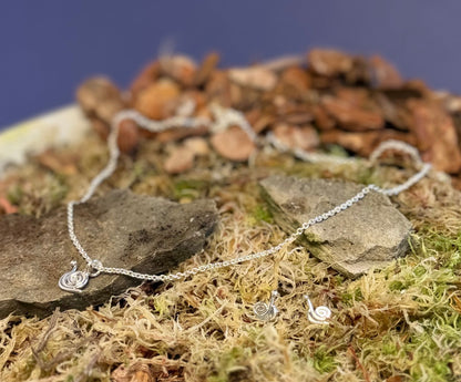 Silver necklace with a snail pendant on a natural stone and moss background