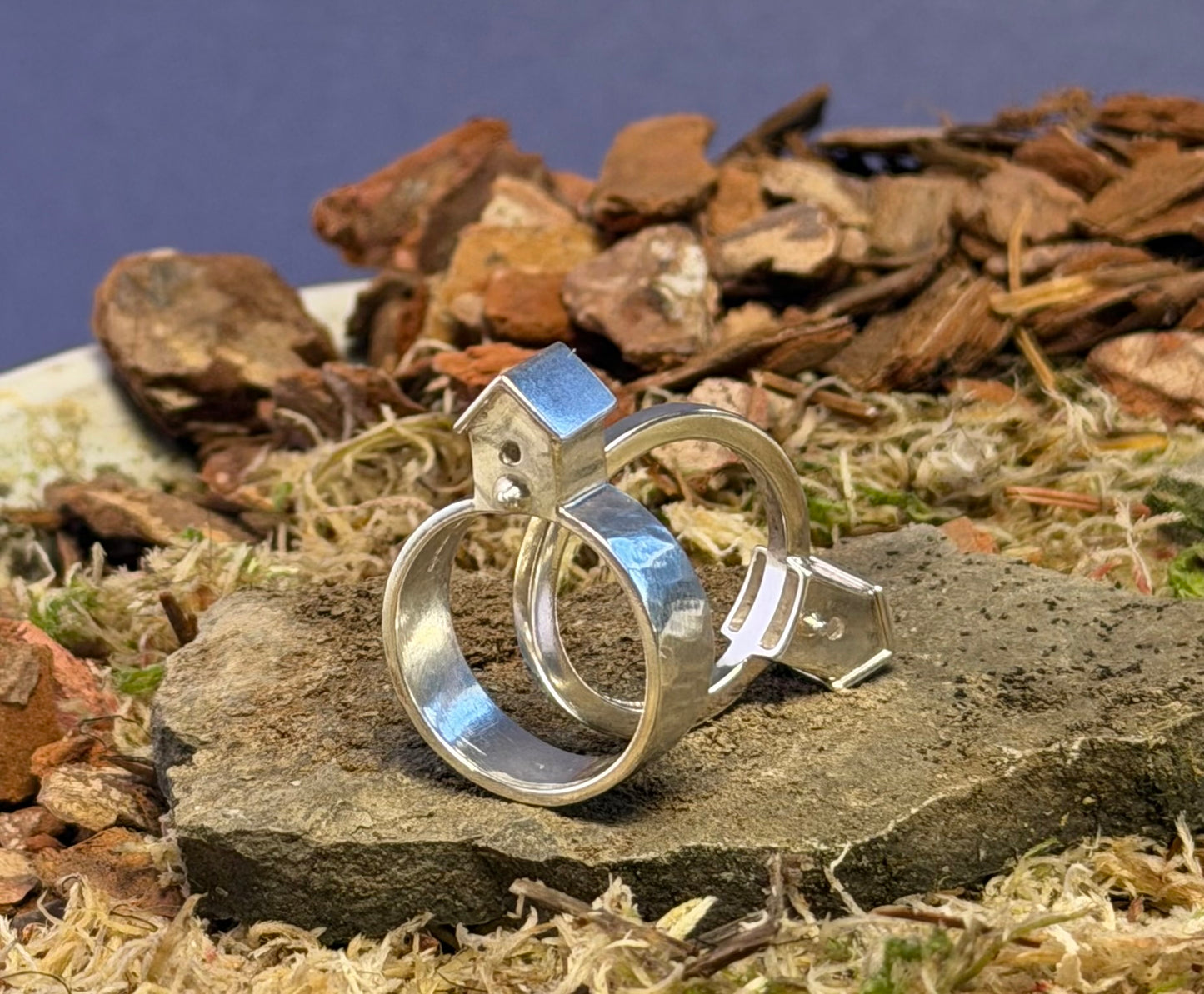 Silver ring with a unique design on a natural stone surface with a rustic background.