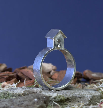 Silver ring with a small birdhouse on a natural background