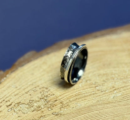 Silver hammered oxidised spinner ring on a wooden surface with a blue background