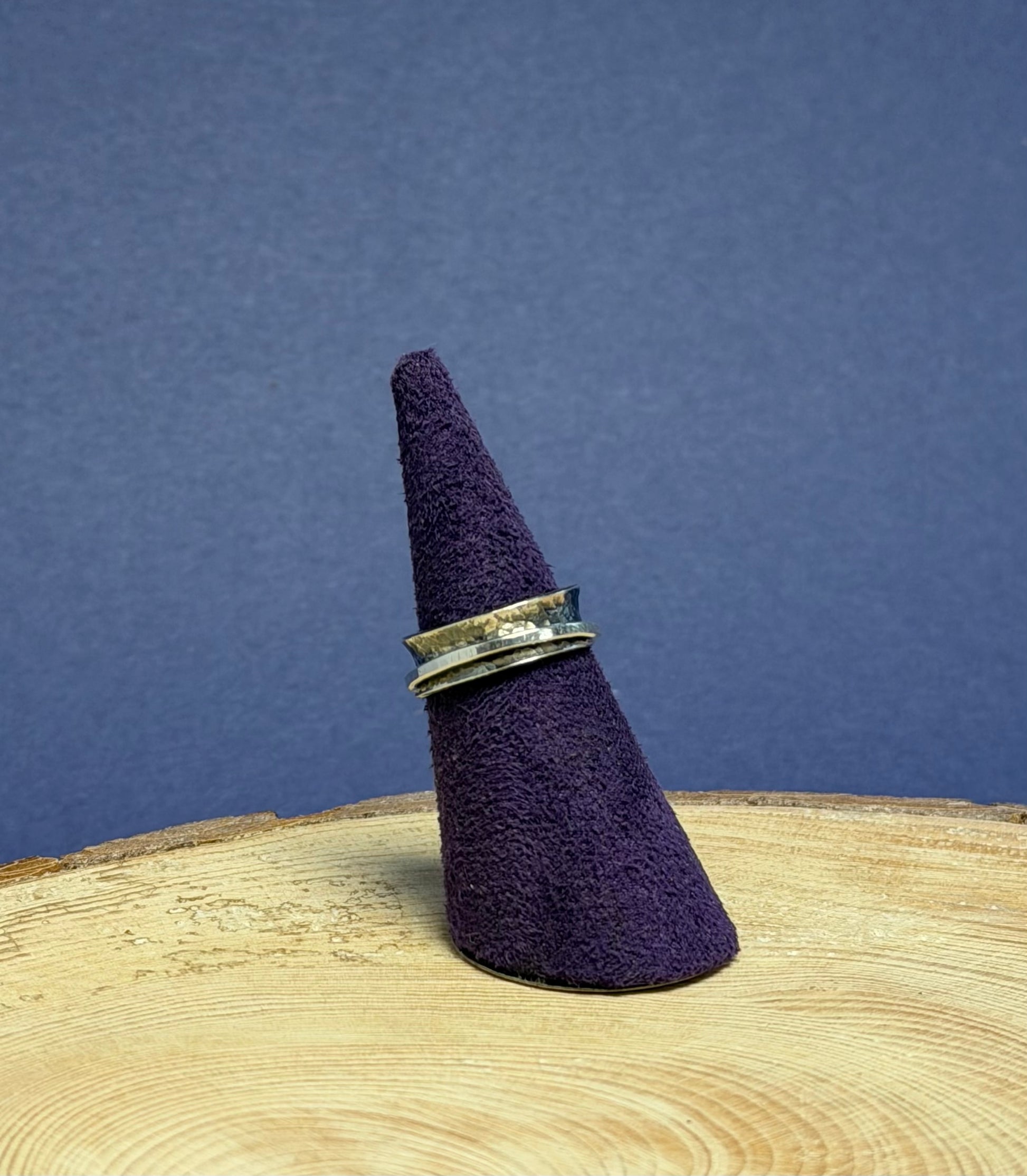 Purple felt cone with a silver ring on a wooden surface against a blue background