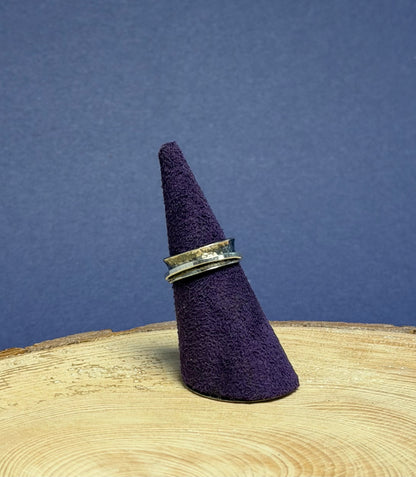 Purple felt cone with a silver ring on a wooden surface against a blue background