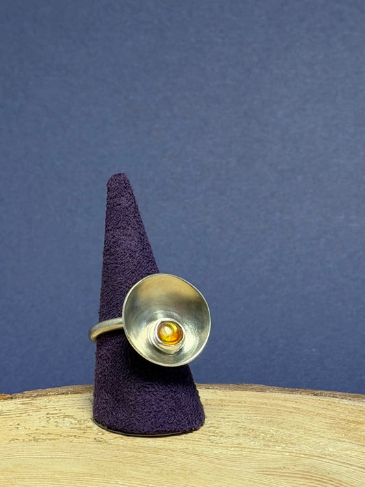 Silver ring on a purple cone against a blue background
