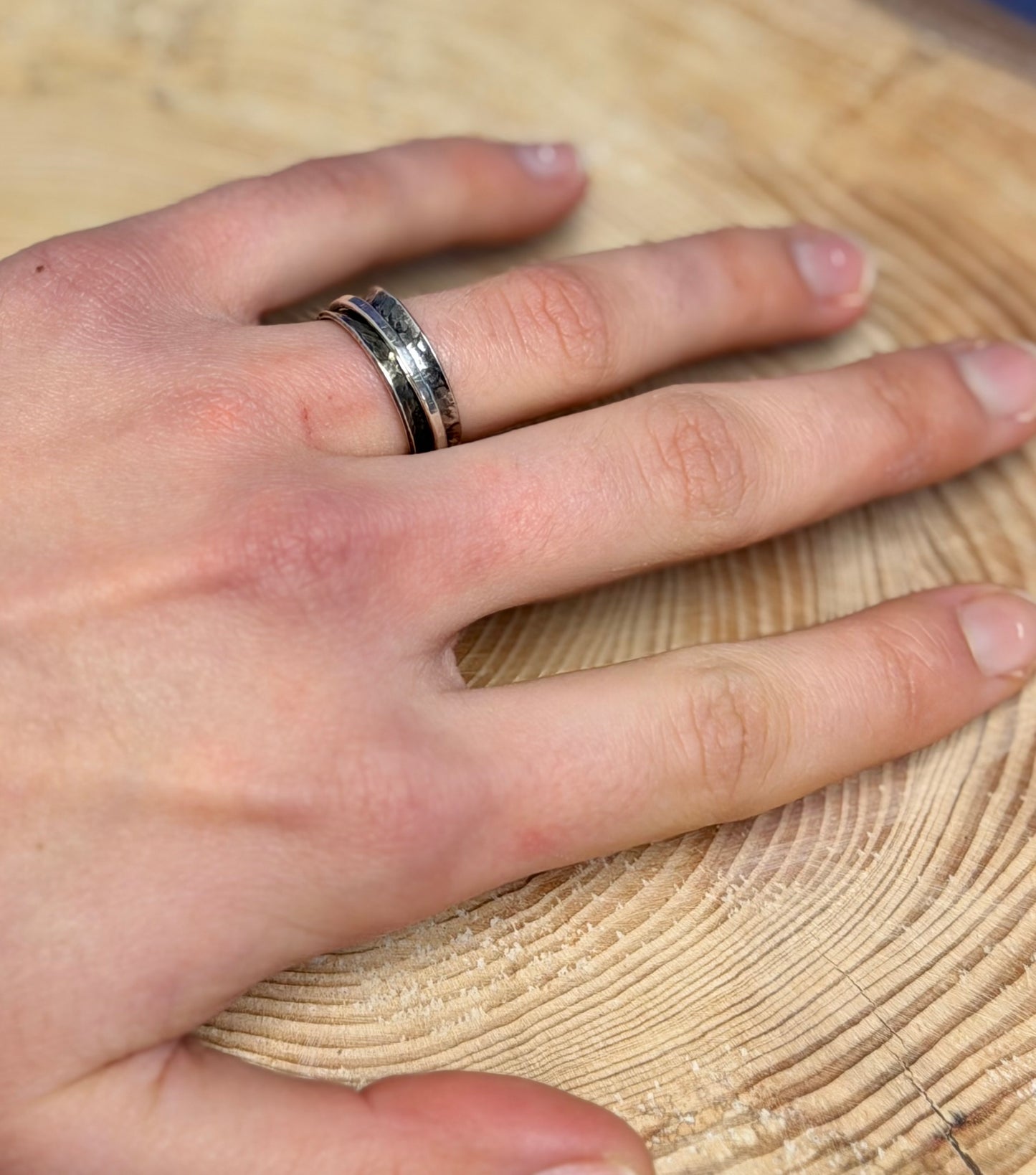 Hand wearing a ring on a wooden surface