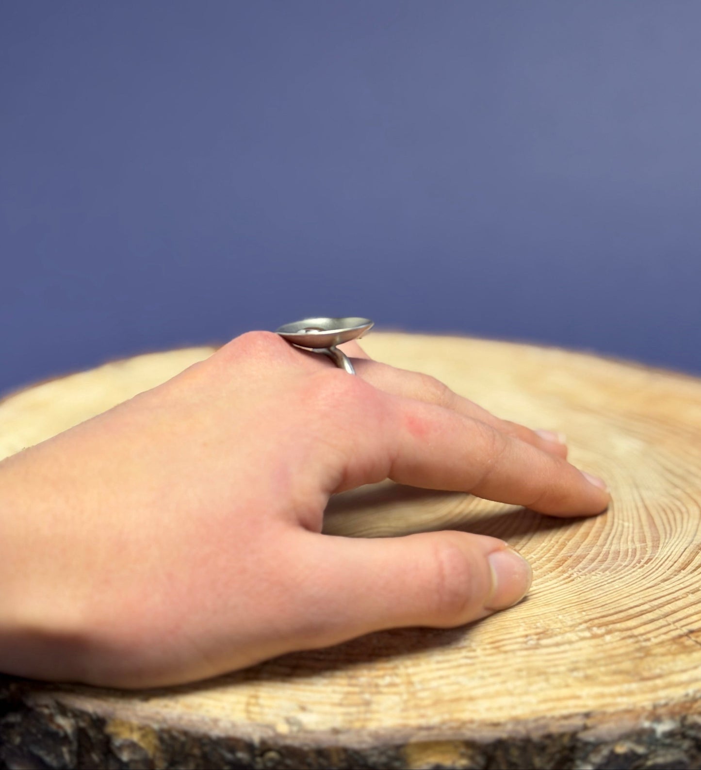 Hand resting on a wooden surface with a blue background