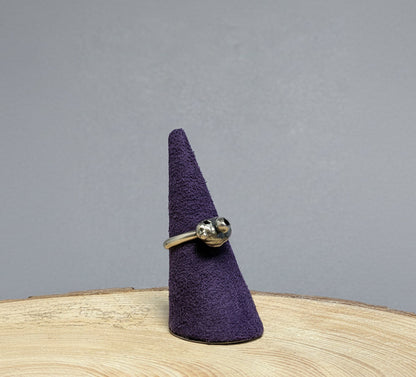 Silver ring on a purple felt cone against a blue background