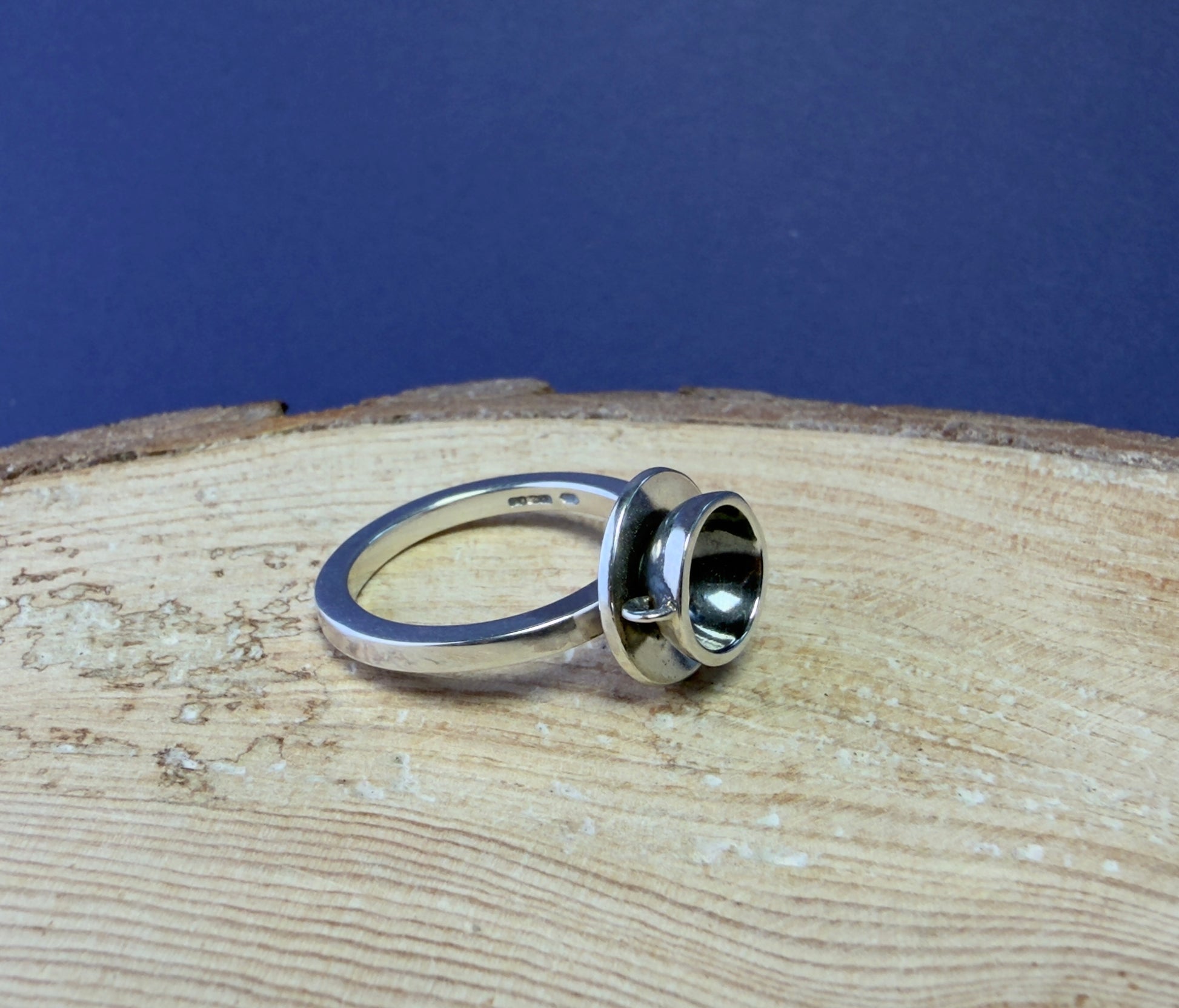 Silver cupcake ring with a unique design on a wooden surface with a blue background