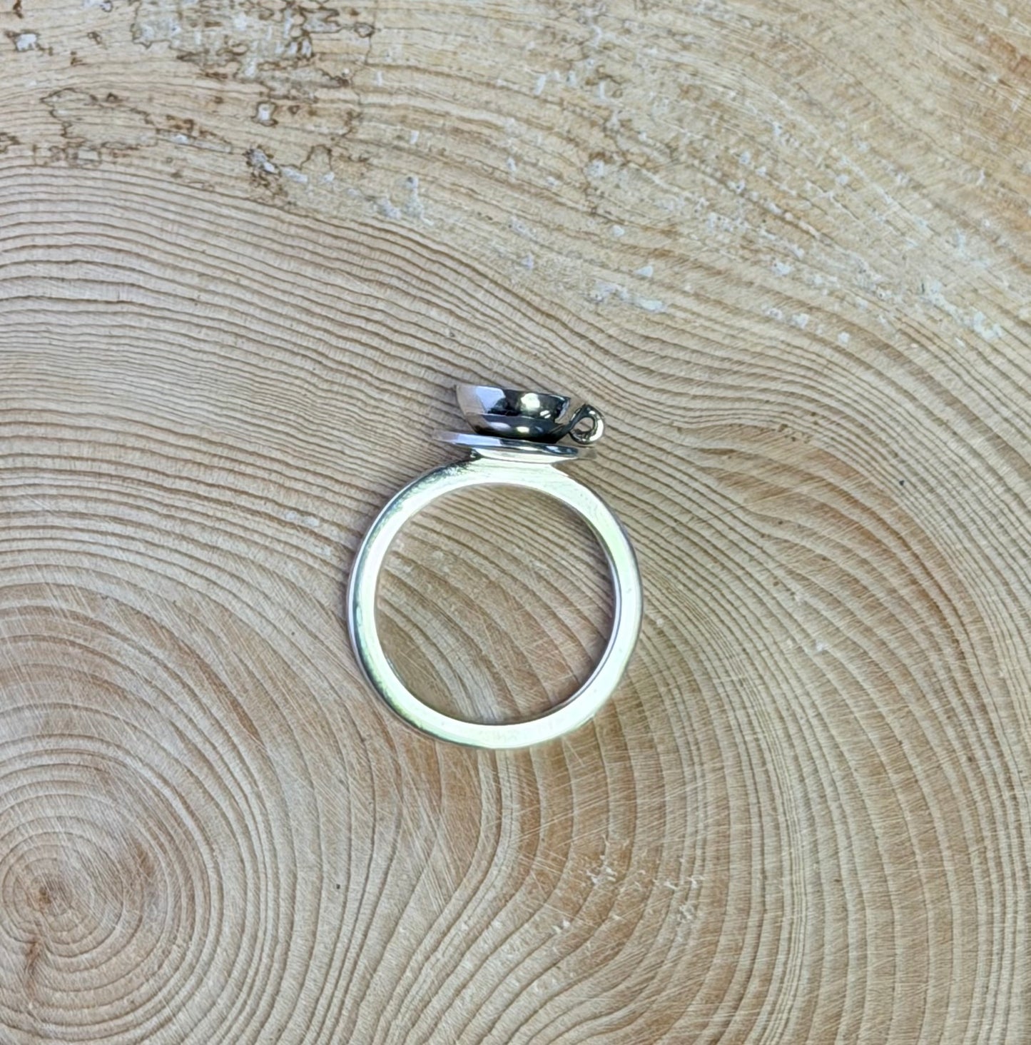 Silver teacup ring on a wooden surface
