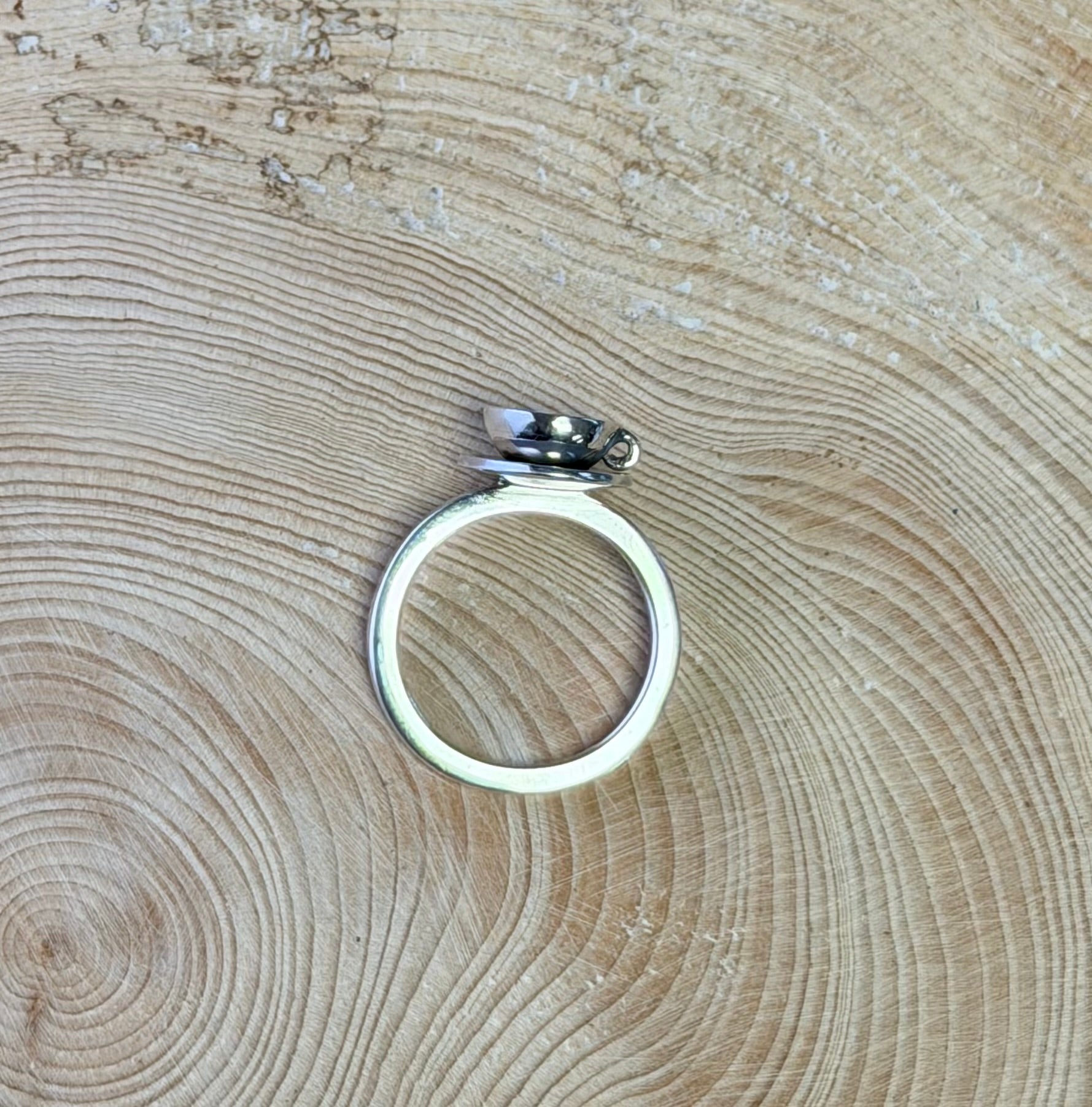 Silver teacup ring on a wooden surface