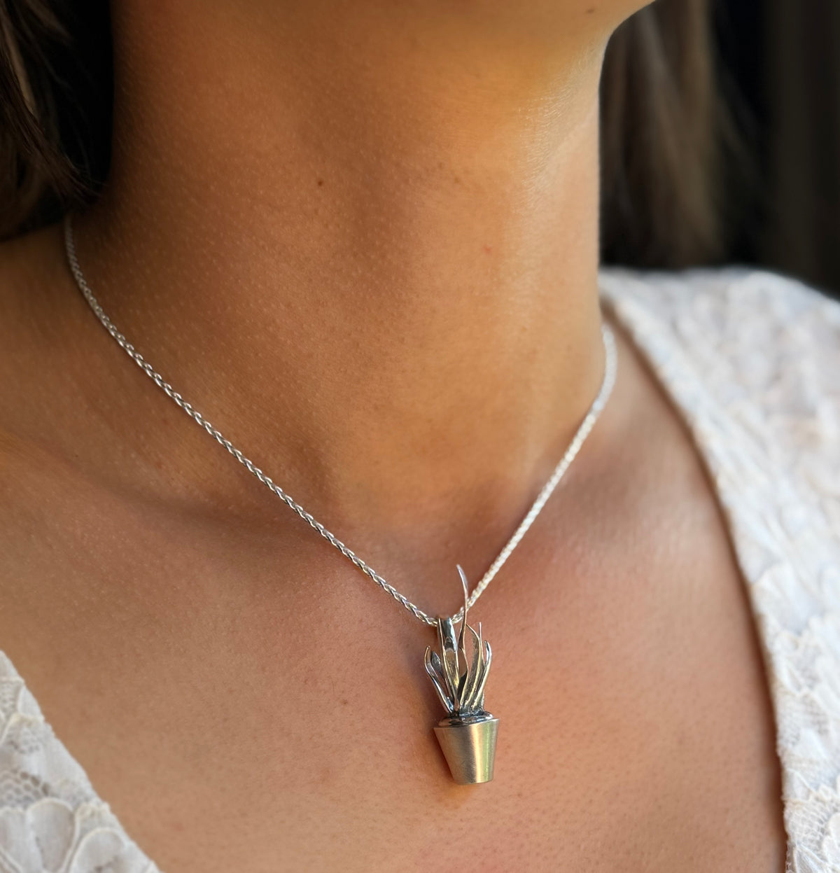 Dracaena trifasciata pendant worn around model’s neck. Colour image.