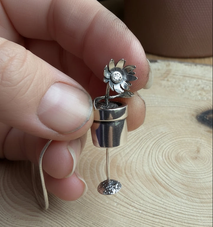 Silver flower pot pendant showing soil underneath