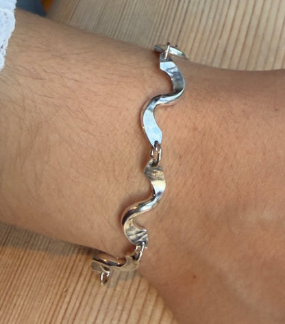 Close-up of the bracelet’s curved twist links, showing the hammered texture and small connecting rings.