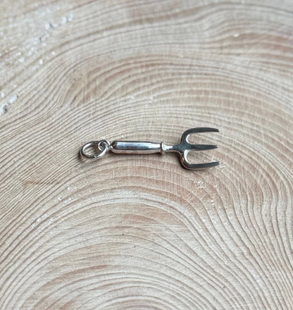 Silver hand fork charm on wood