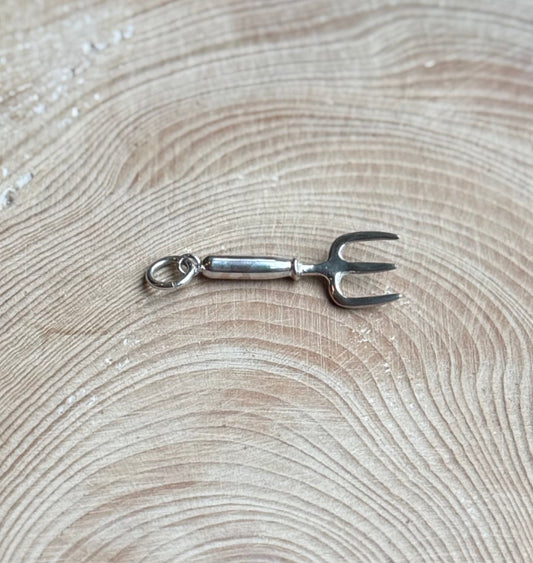 Silver hand fork charm on wood