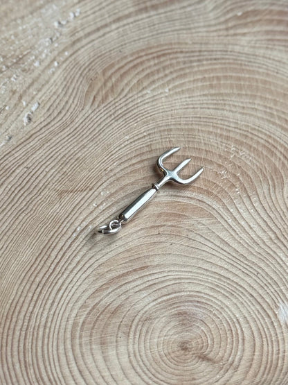 Silver hand fork charm on wooden background