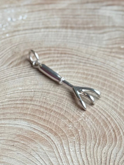 Hand cultivator charm on wooden table