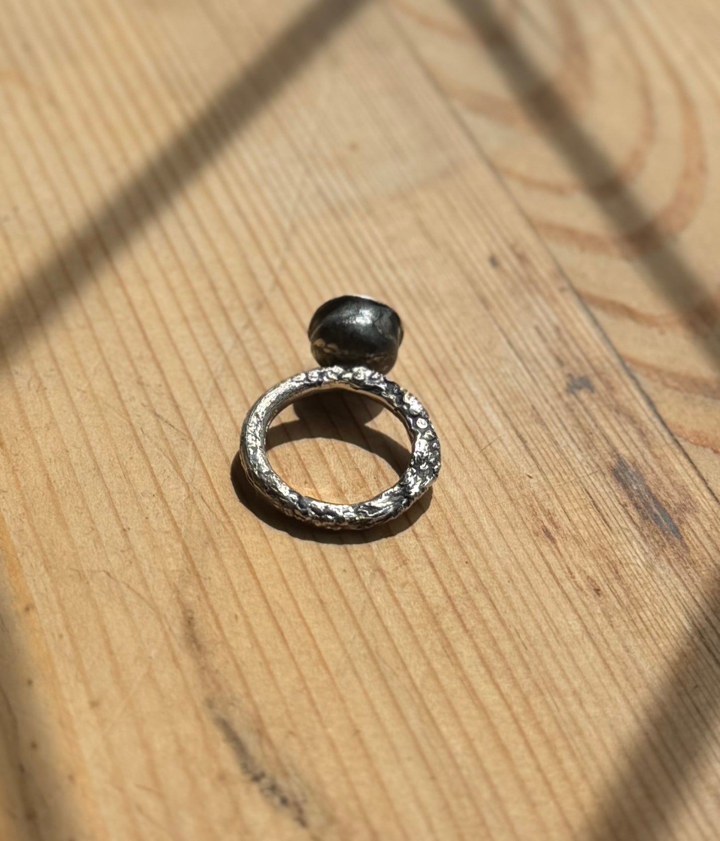 molten silver cup ring on wood