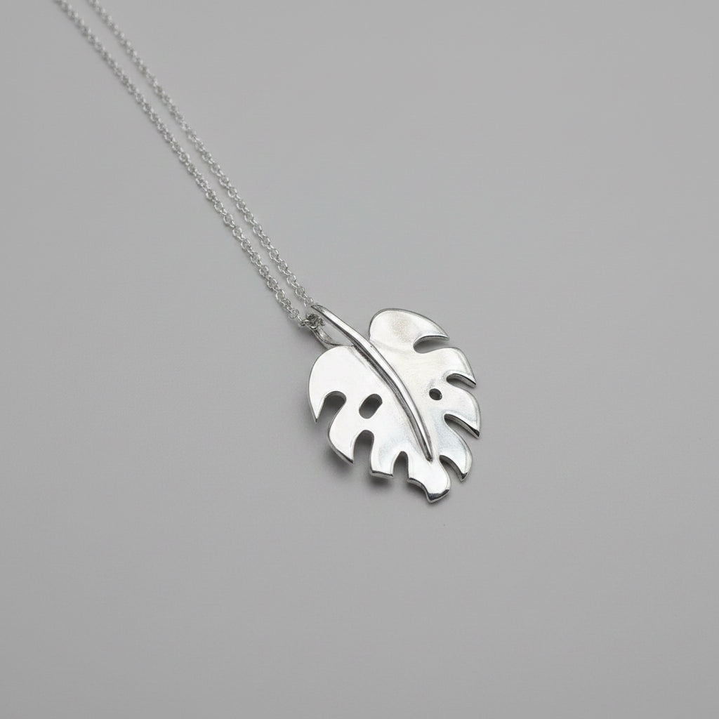 Monstera leaf pendant on chain, with a grey background