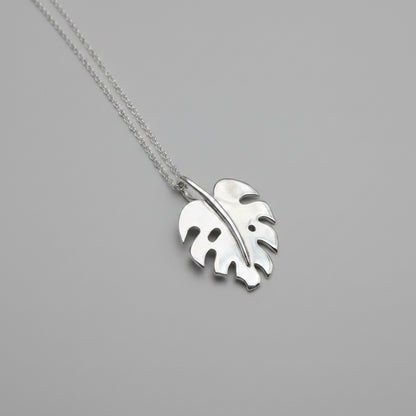 Monstera leaf pendant on chain, with a grey background