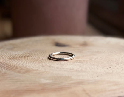 Silver round profile ring band, placed on wood