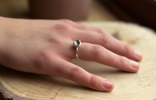 Silver molten ring band on hand resting on wood
