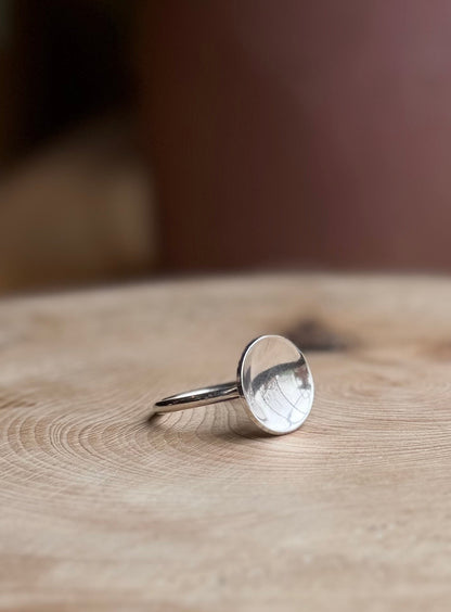 Silver slim band with polished dome resting on wood