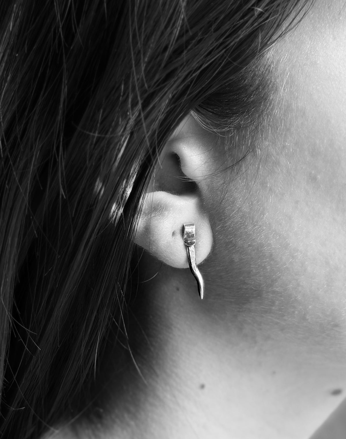 Small spike stud in model’s ear. Black and white image.