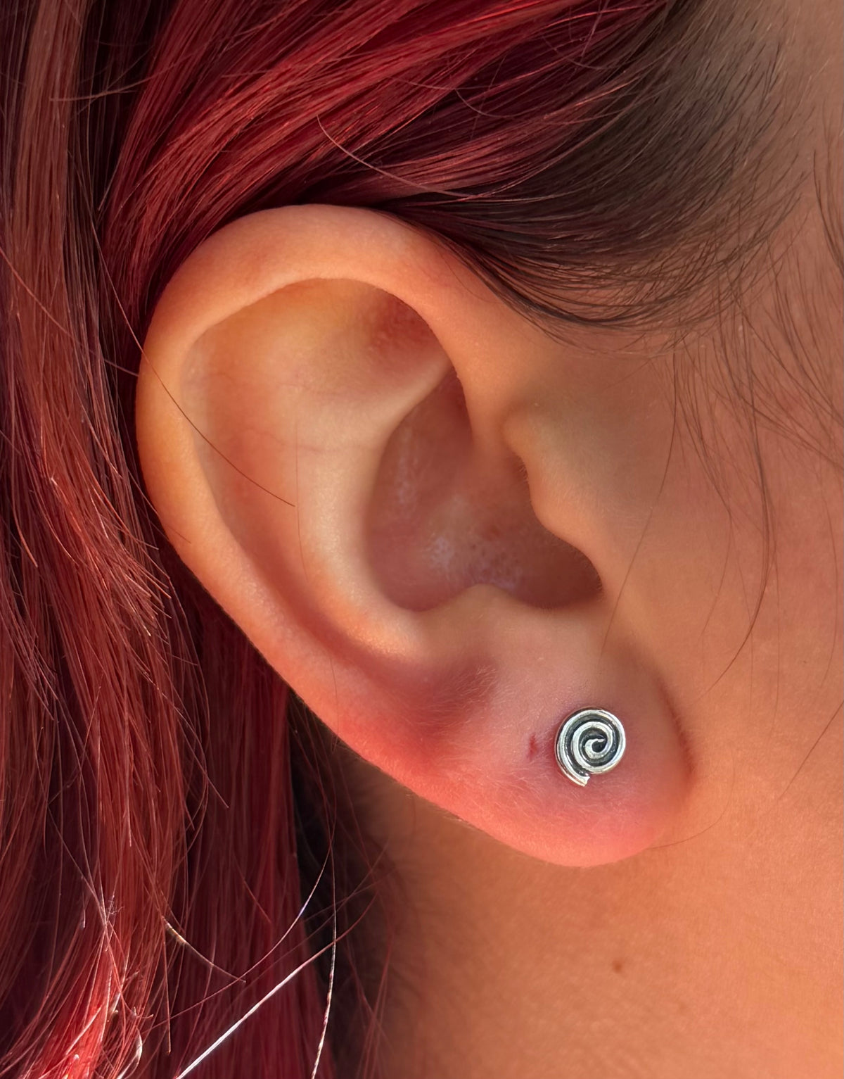 Tiny spiral stud in ear. Colour image.