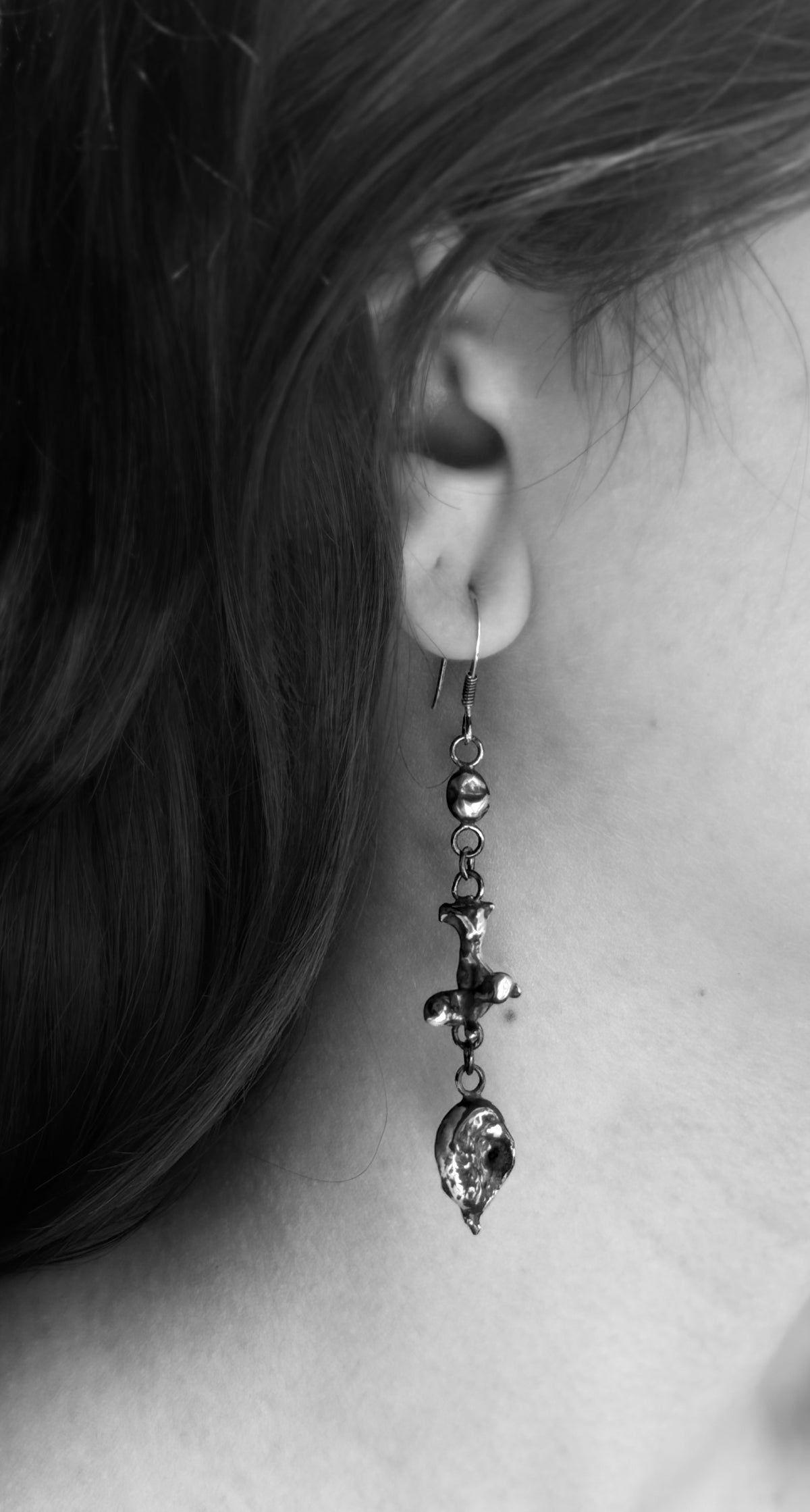 Black-and-white close-up of a silver nugget drop earring, showing its rounded top nugget, sculptural middle and textured lower nugget.