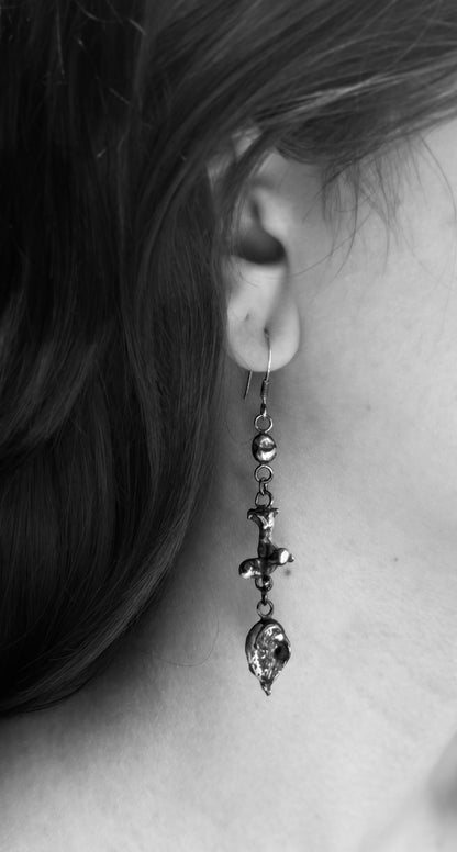 Black-and-white close-up of a silver nugget drop earring, showing its rounded top nugget, sculptural middle and textured lower nugget.