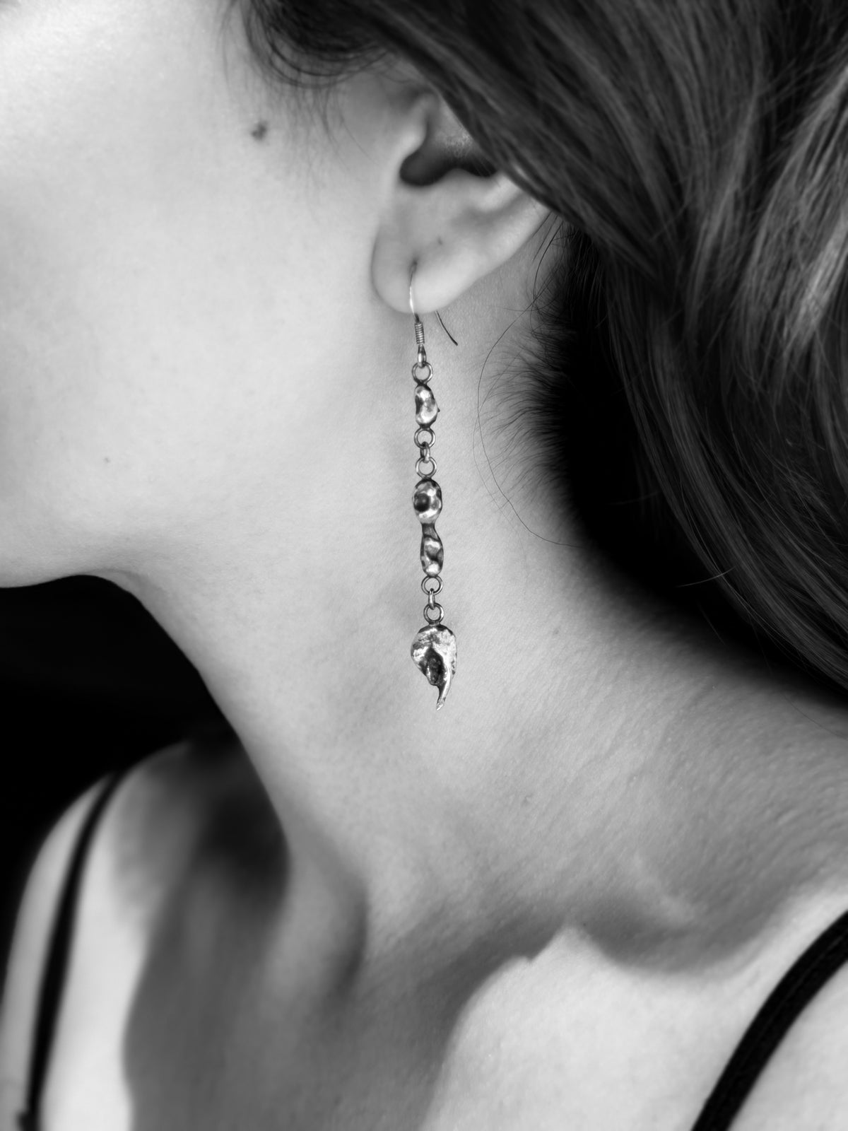 Black-and-white view of an Alchemy silver nugget earring worn from a hook fastening, with the full drop visible.