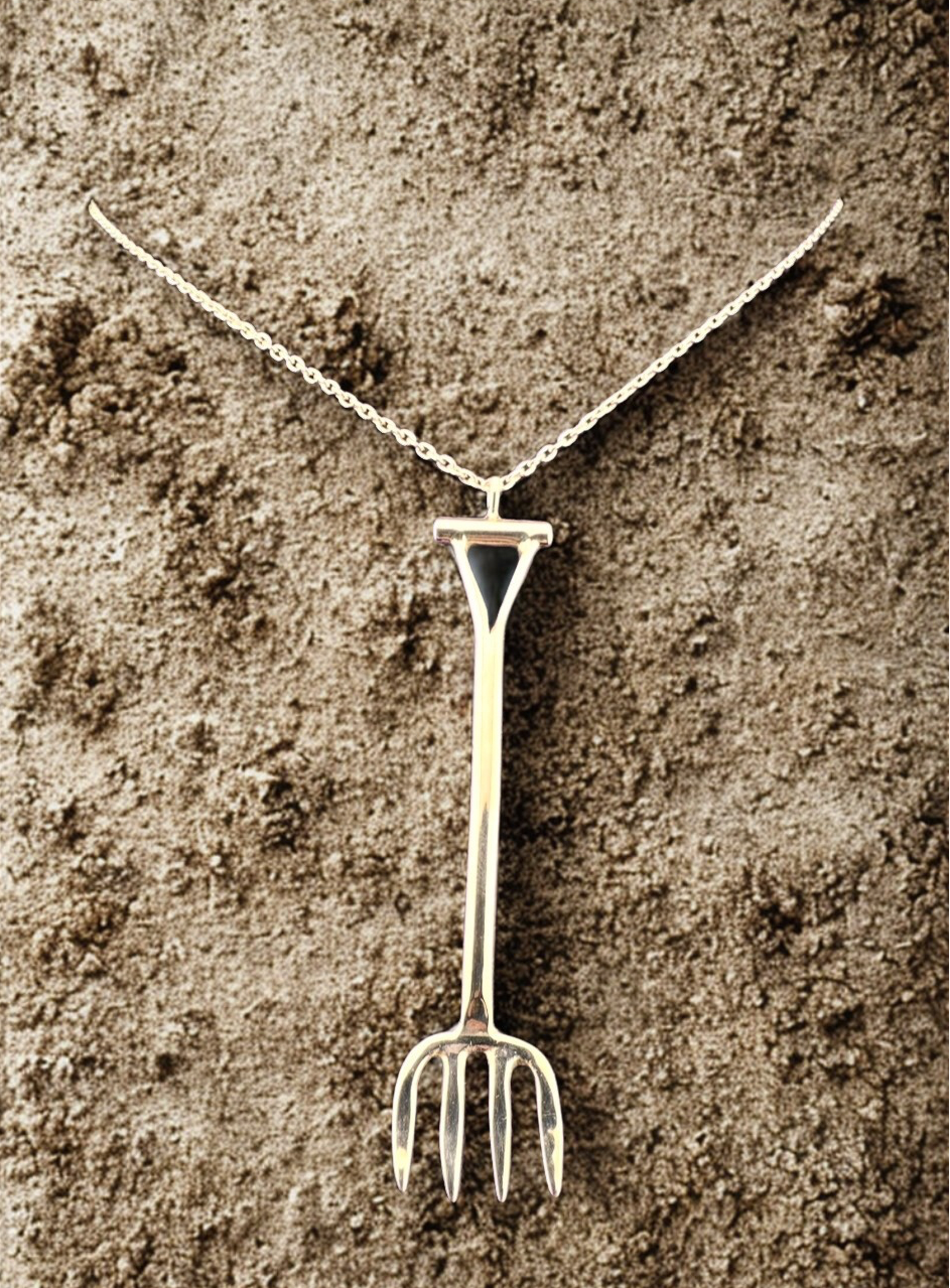 Silver necklace with a unique pendant shaped like a garden fork on a textured brown background