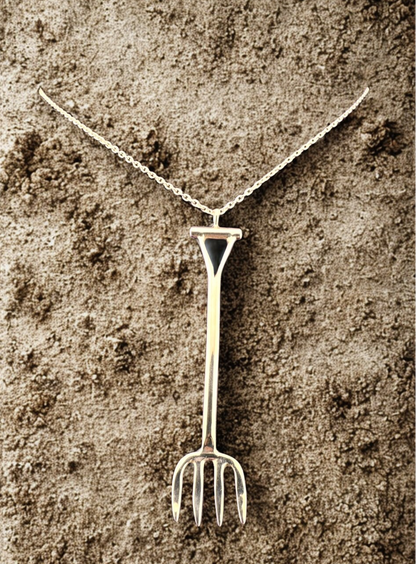 Silver necklace with a unique pendant shaped like a garden fork on a textured brown background