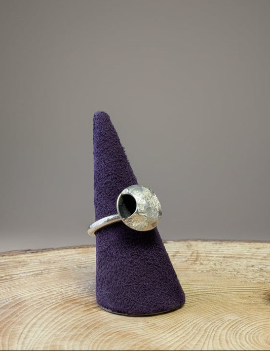 Silver ring with a moon design on a purple cone-shaped stand against a blue background